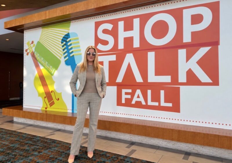 Julie Wohlberg stands in front of the Shoptalk Fall sign at the Nashville conference