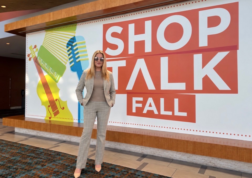 Julie Wohlberg stands in front of the Shoptalk Fall sign at the Nashville conference