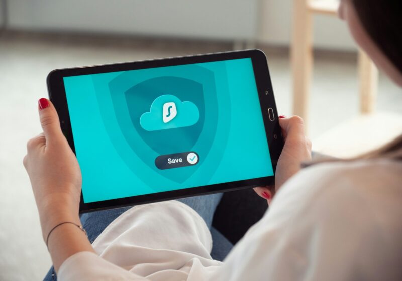 Person holding a black tablet displaying a Surfshark screen; not an Amazon device