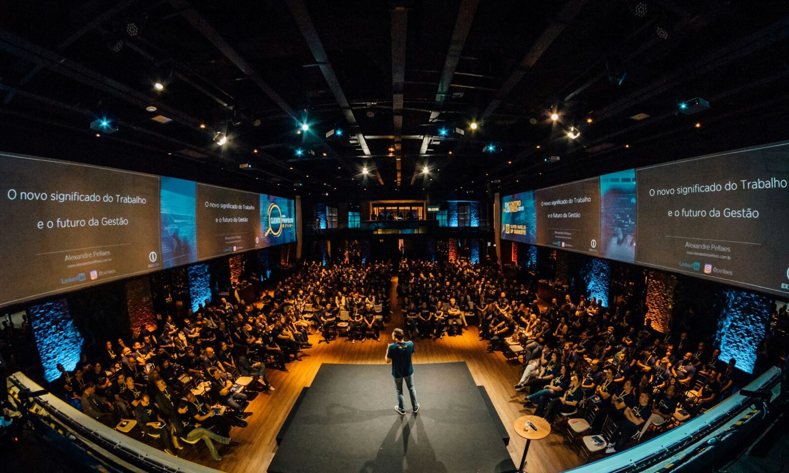 A speaker on stage addressing a large seated audience
