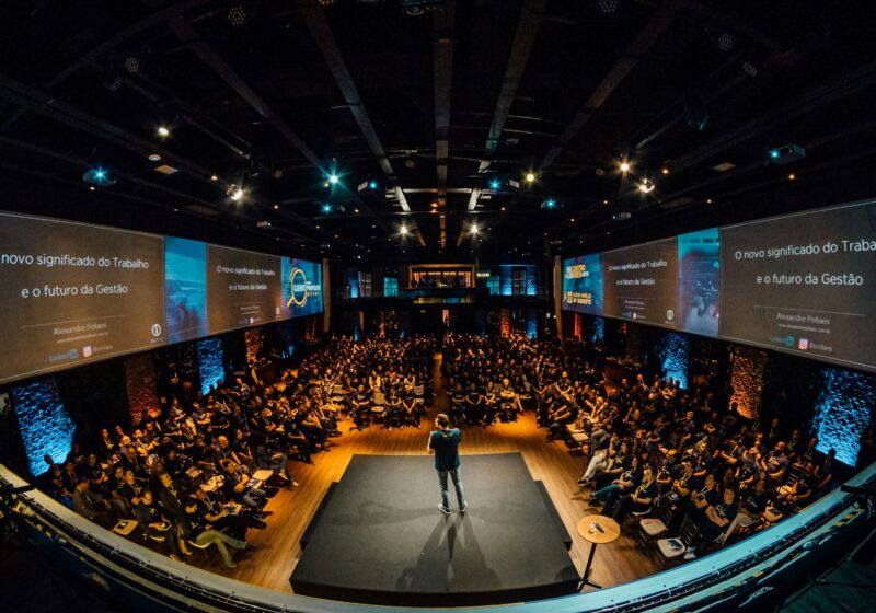 A speaker on stage addressing a large seated audience