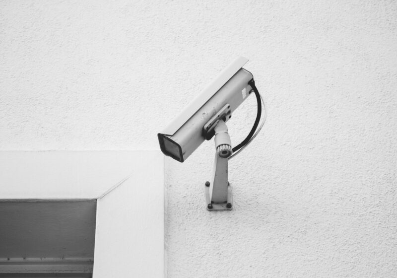 A surveillance camera mounted on a textured white wall