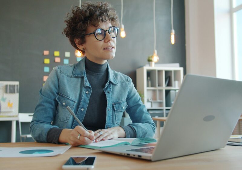 Woman working alone at a desk with a laptop and notebook
